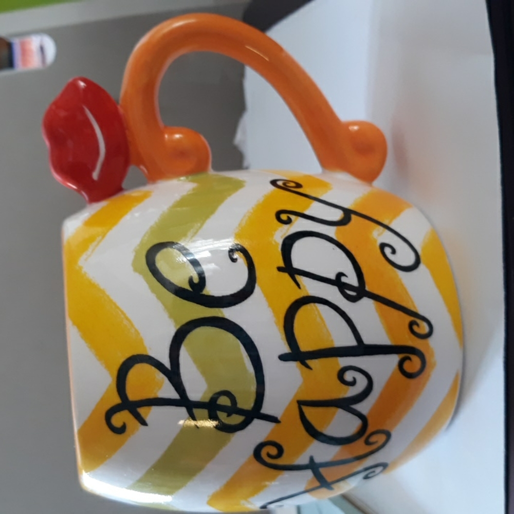 A mug stating BE HAPPY in beautiful colors.